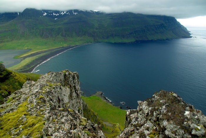 Grýttur útsýnisstaður yfir vík og græna strandkletta